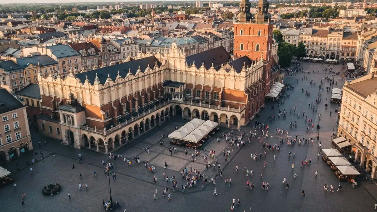 Rynek Główny w Krakowie widziane z lotu ptaka ze Sukiennicami pośrodku, kolorowe budynki, turyści na placu, jasny dzień
